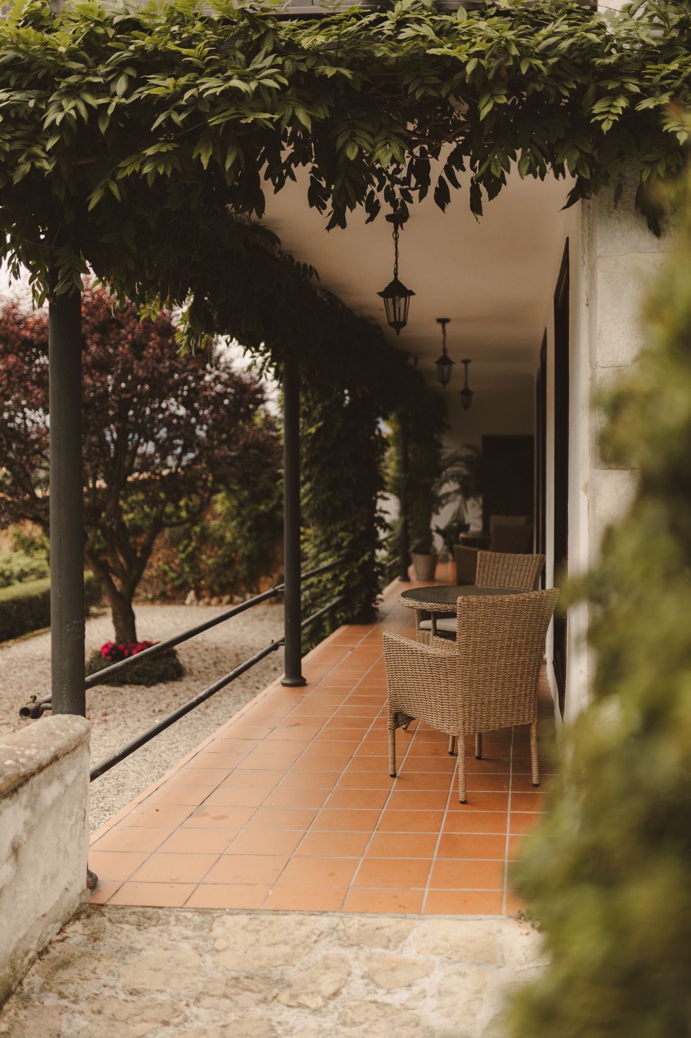 A porch with a row of chairs under a pergola.