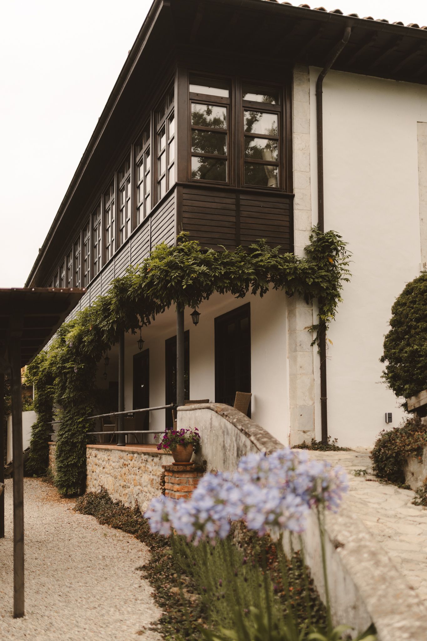 A large white house with purple flowers in front of it.