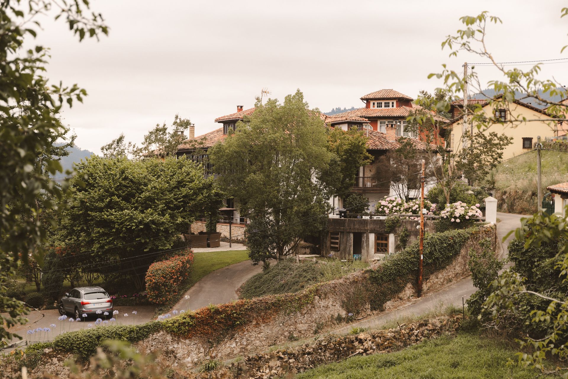 A car is driving down a road in front of a house.