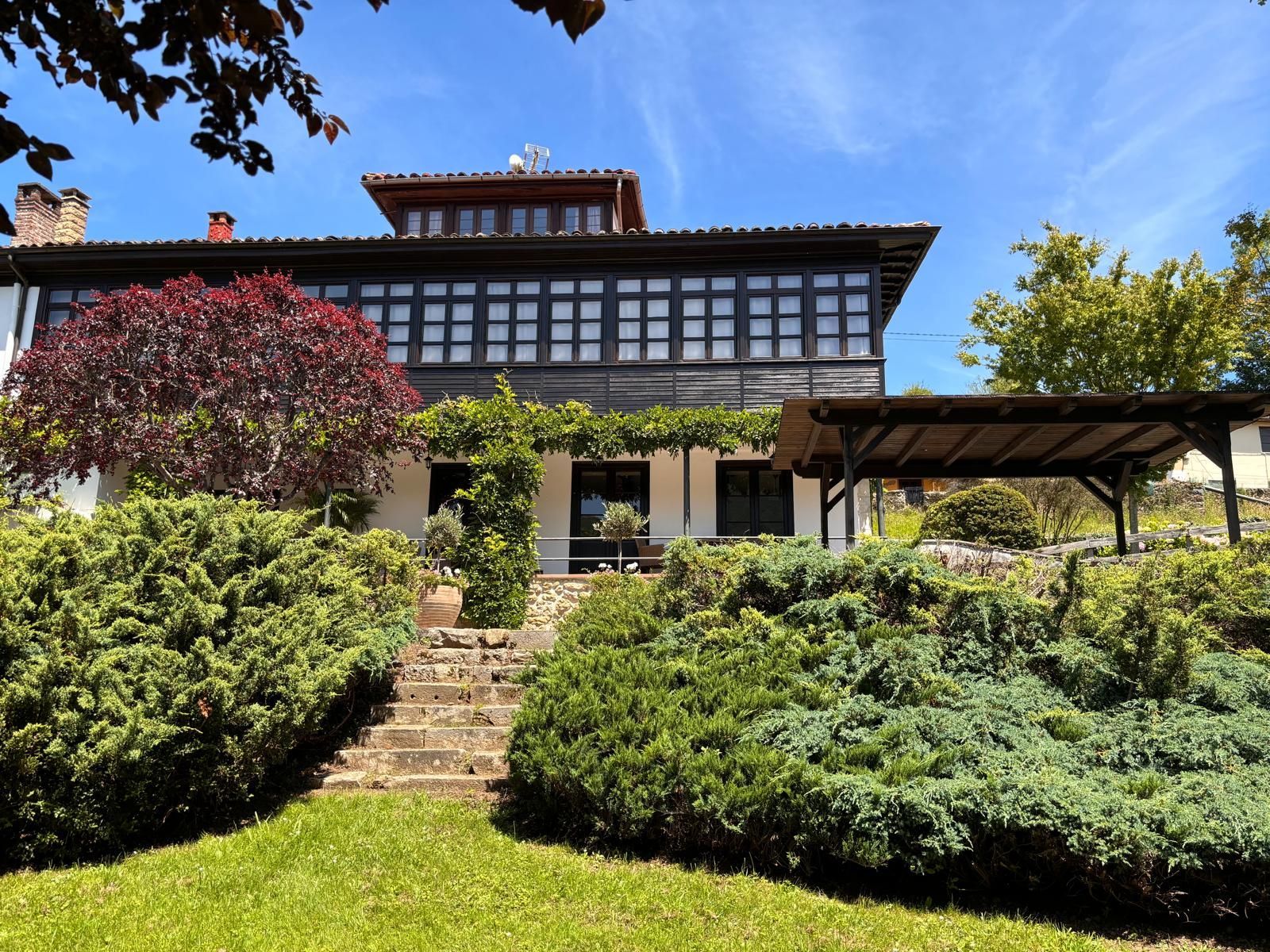 A large house is surrounded by bushes and trees