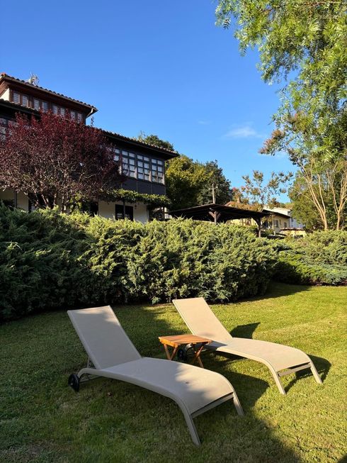 Two lounge chairs are sitting in the grass in front of a house.