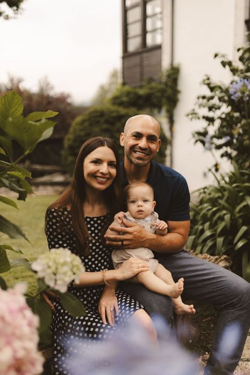 A man and woman are sitting on a bench holding a baby.
