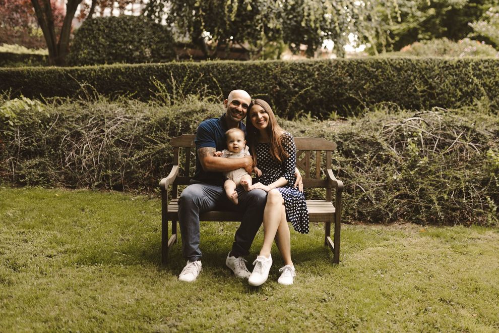 A man and woman are sitting on a bench with a baby.