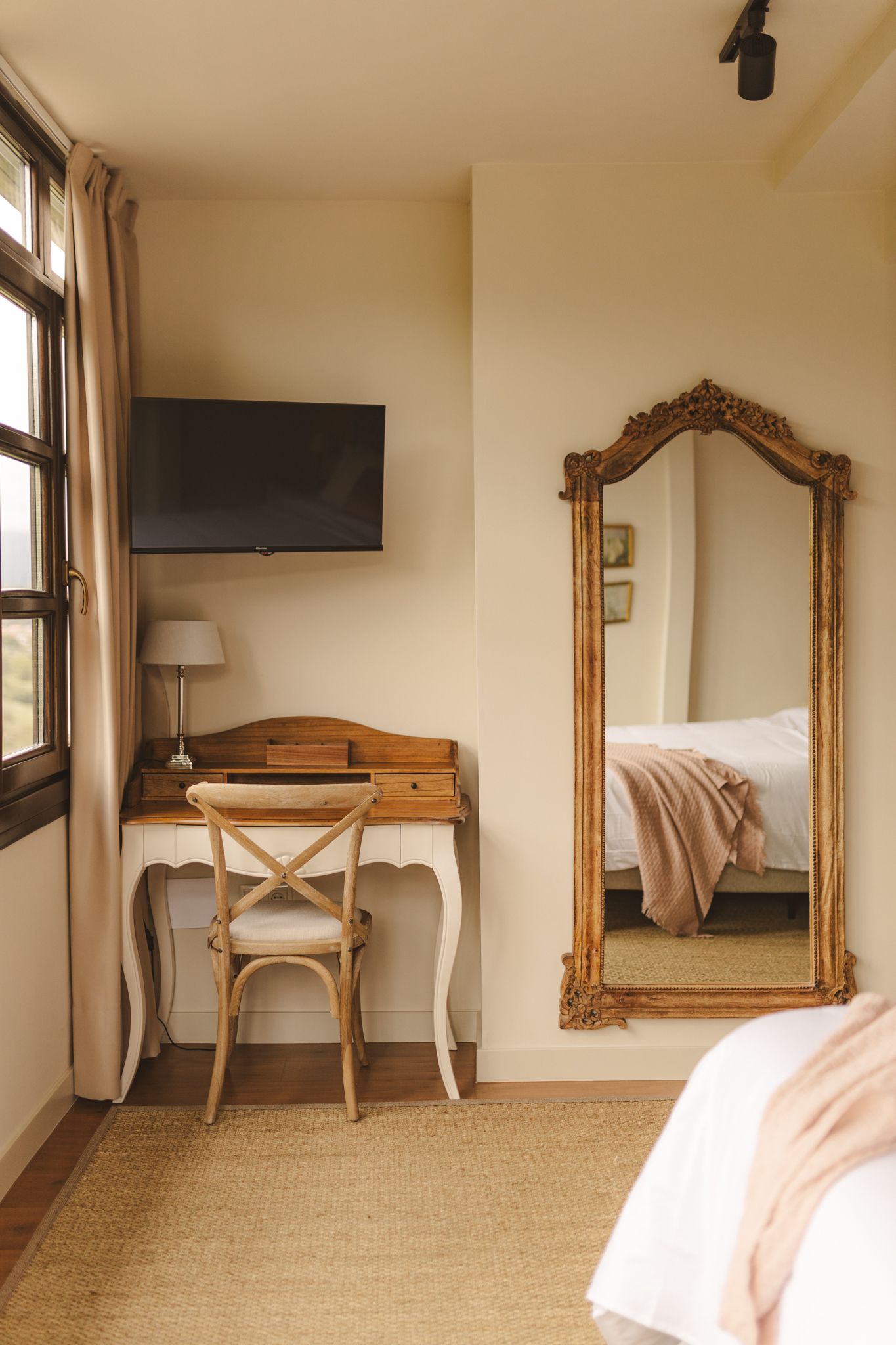 A bedroom with a desk , chair , television and mirror.