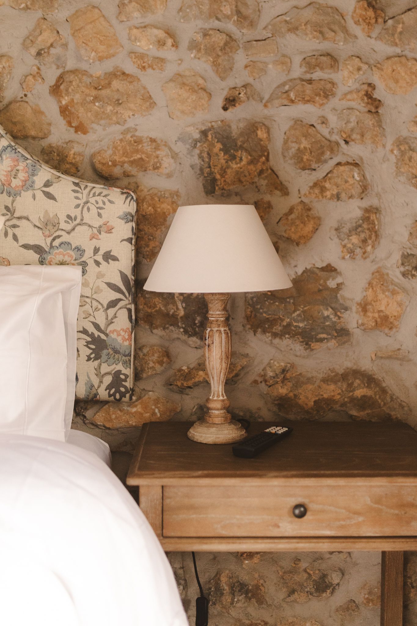 A lamp is sitting on a nightstand next to a bed in a bedroom.