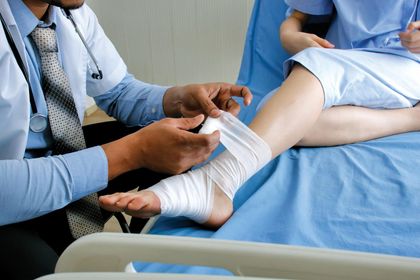 Doctor Putting Bandage On Injured Feet Of Patient — Douglas, GA — Farrar, Hennesy & Tanner LLC