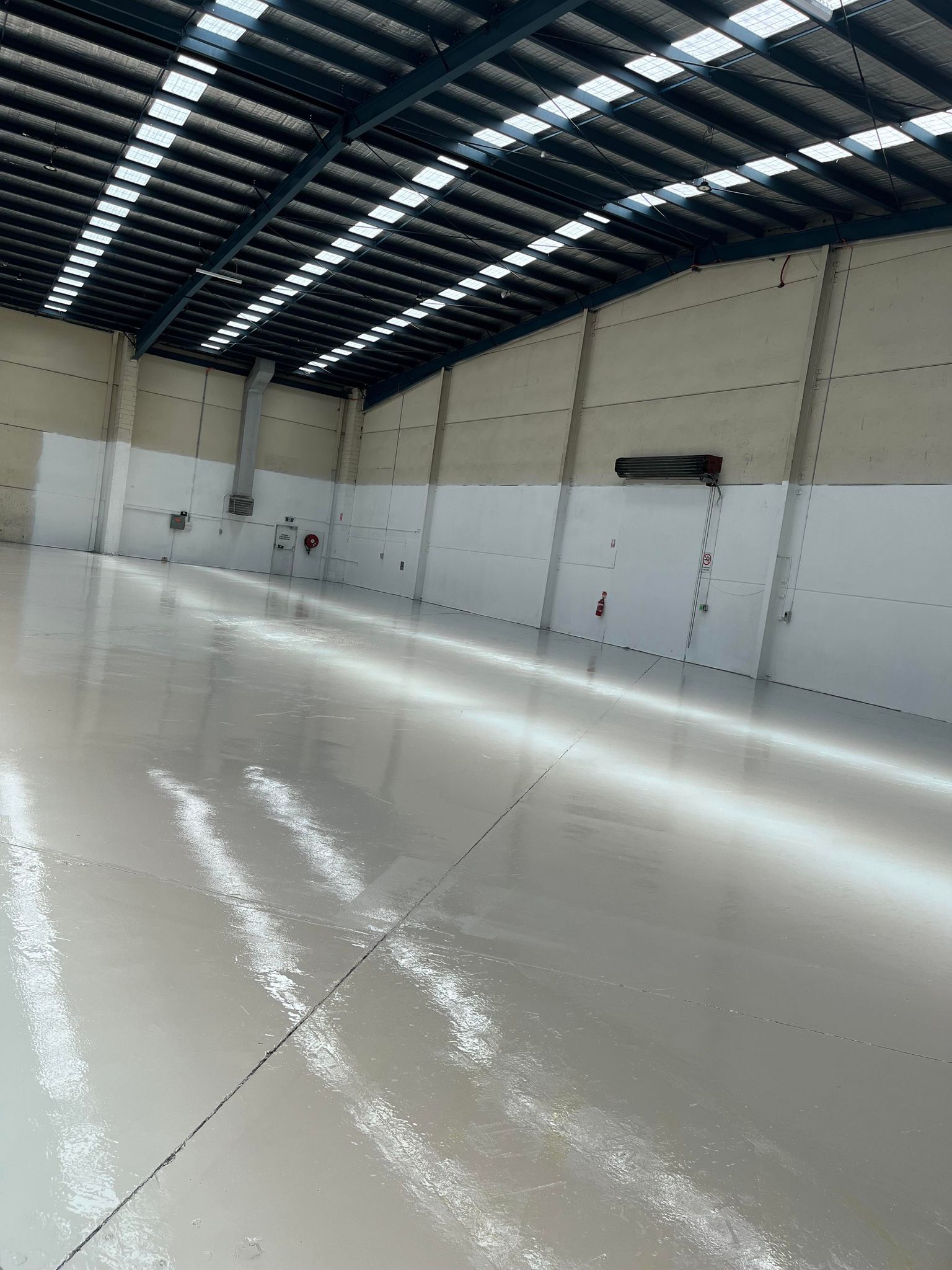 A large warehouse with a white floor and a blue roof