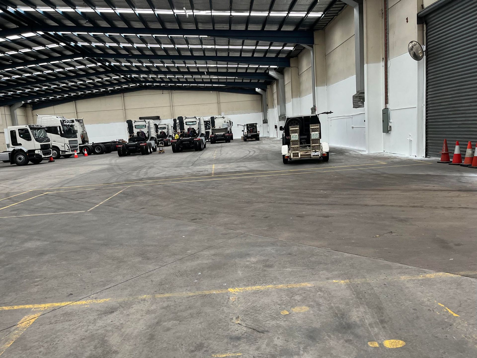 A large warehouse filled with trucks and forklifts