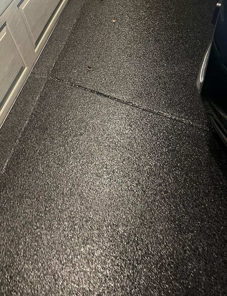 A car is parked in a garage with a black floor