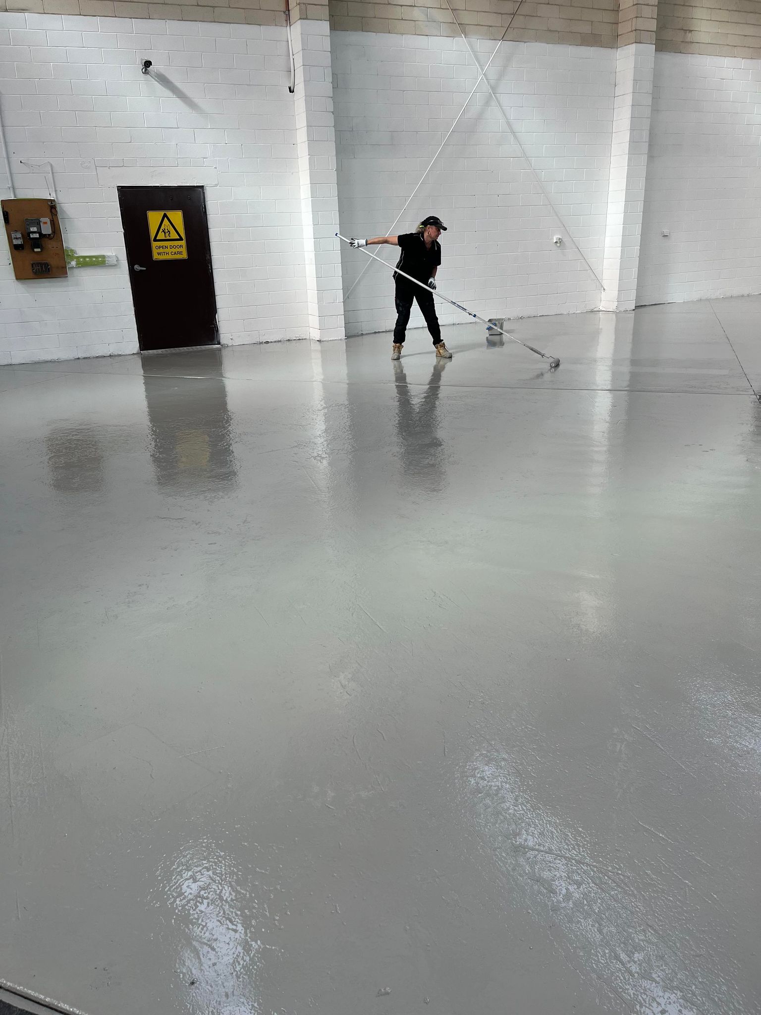 A man is standing on a wet floor in front of a caution sign