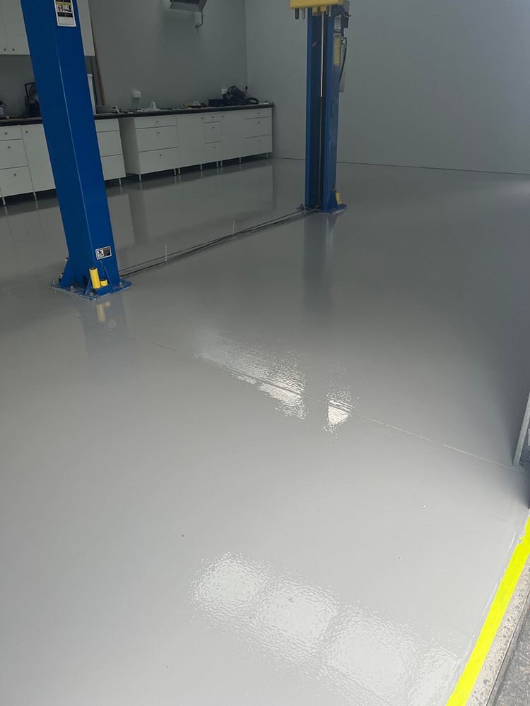 A garage with a blue lift and a white floor