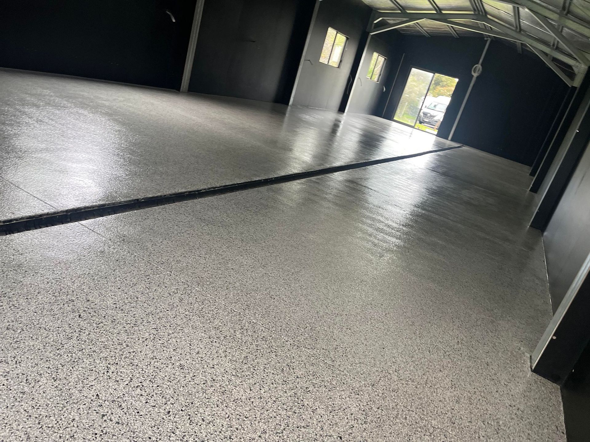 A garage with a concrete floor and a black door