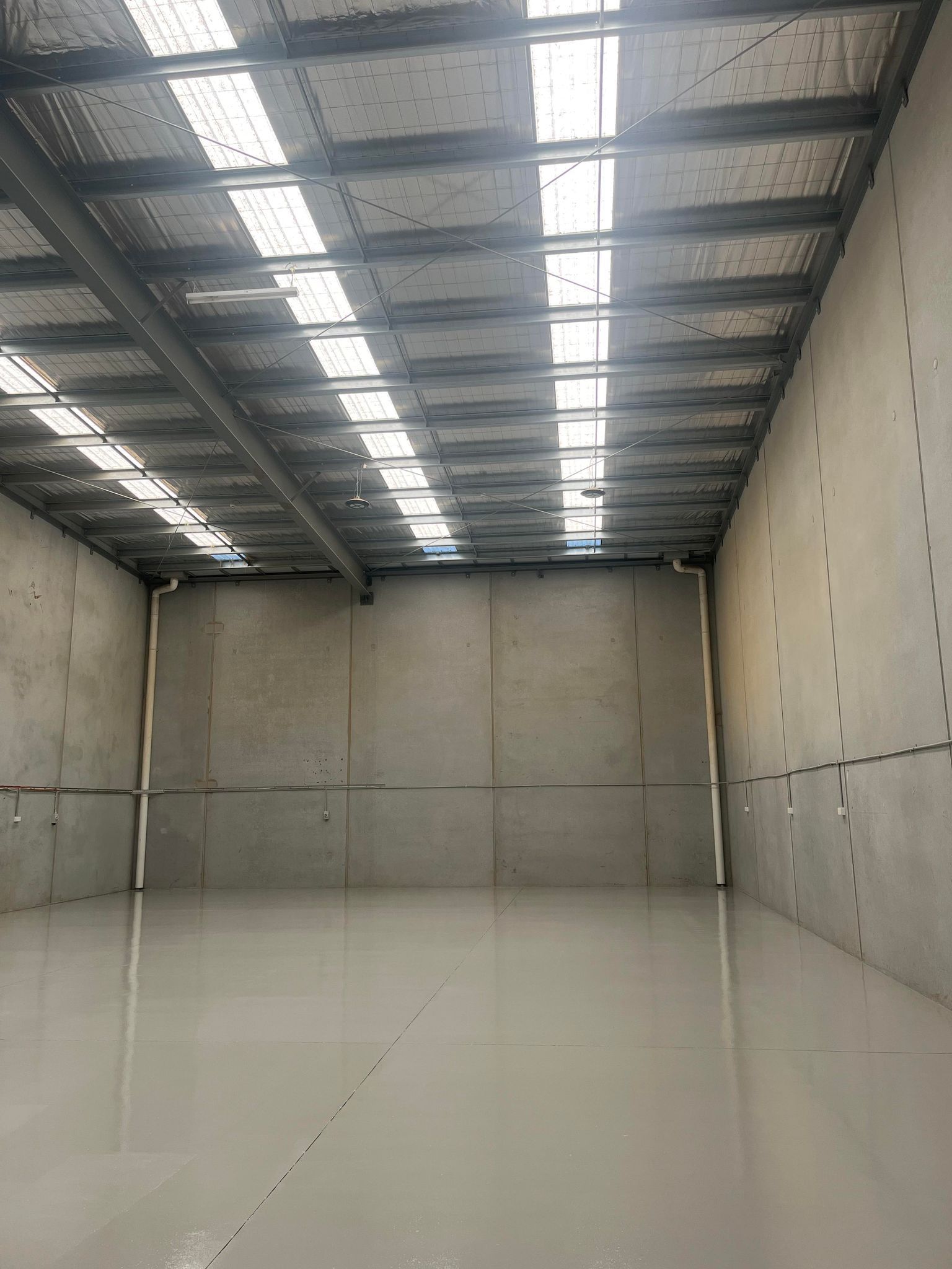 An empty warehouse with a concrete floor and a metal roof