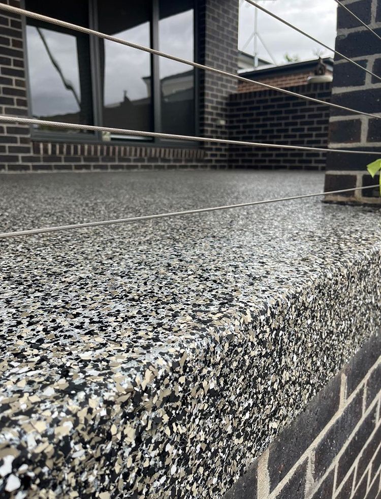 A balcony with a brick wall and a stainless steel railing