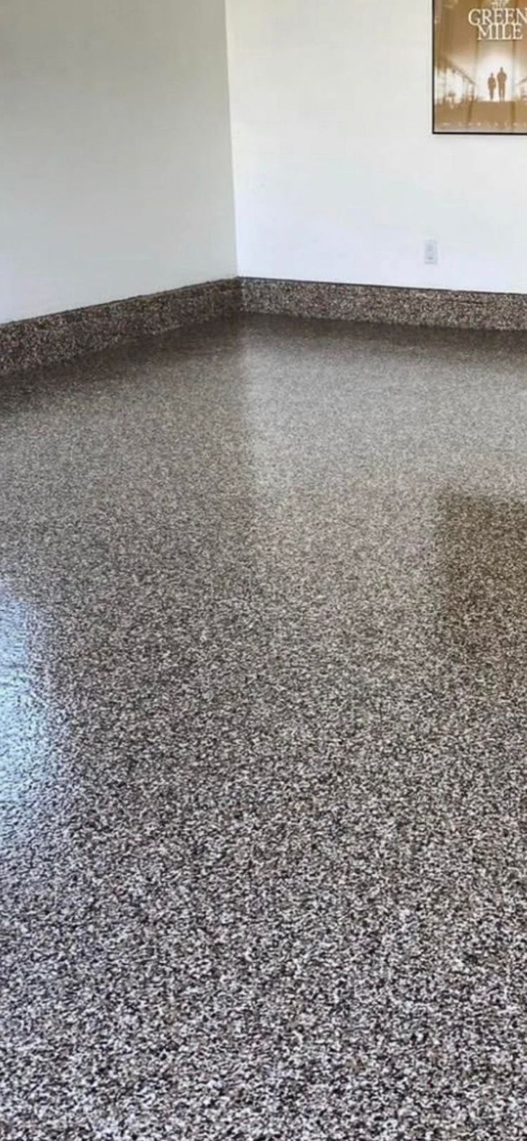 A close up of a shiny gray floor with a yellow pole in the background