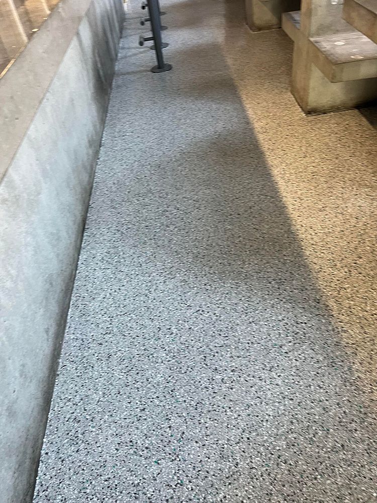 A concrete walkway with a bench on the side of it