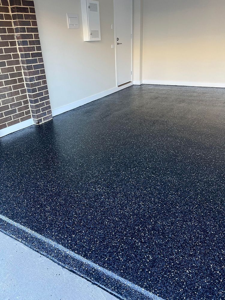 A garage with a black floor and a brick wall