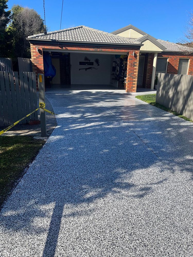 A driveway leading to a house with a garage and a fence