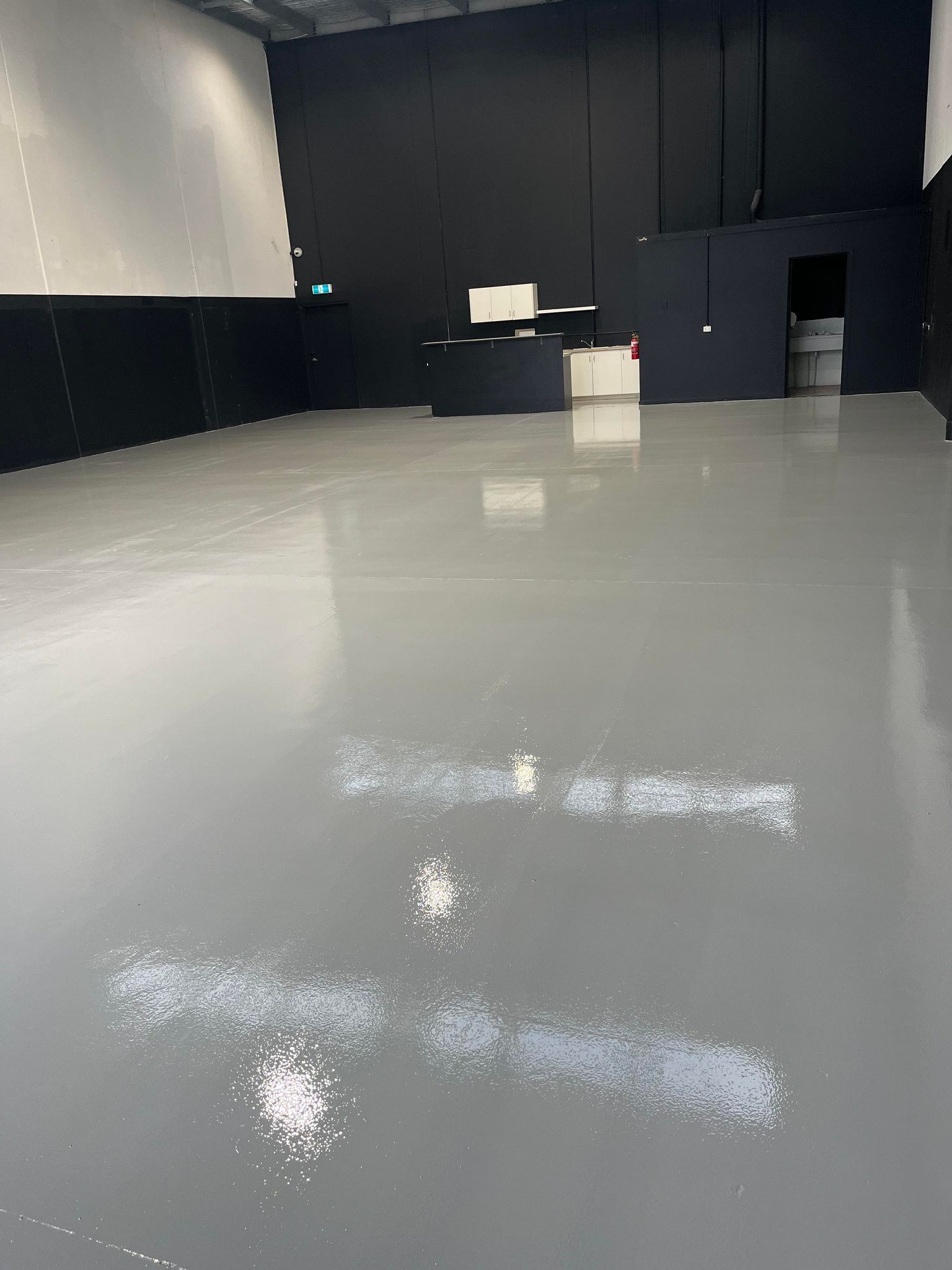 A large empty warehouse with a gray floor and black walls