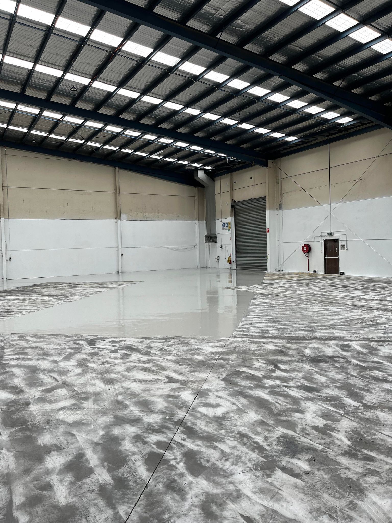 A large empty warehouse with a concrete floor and white walls