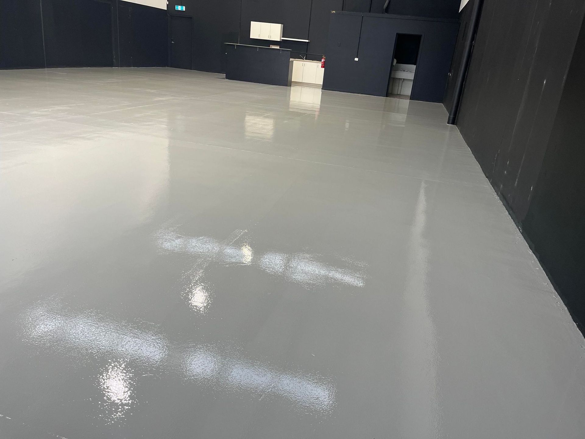 A large empty room with a gray floor and black walls