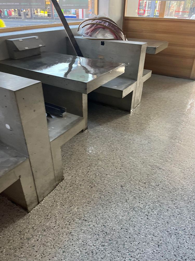 A row of stainless steel tables and benches in a restaurant