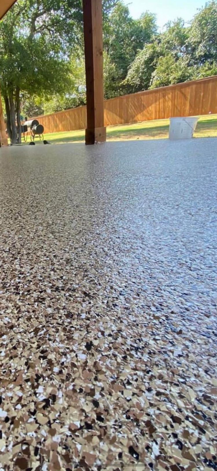 A close up of a concrete floor with a fence in the background