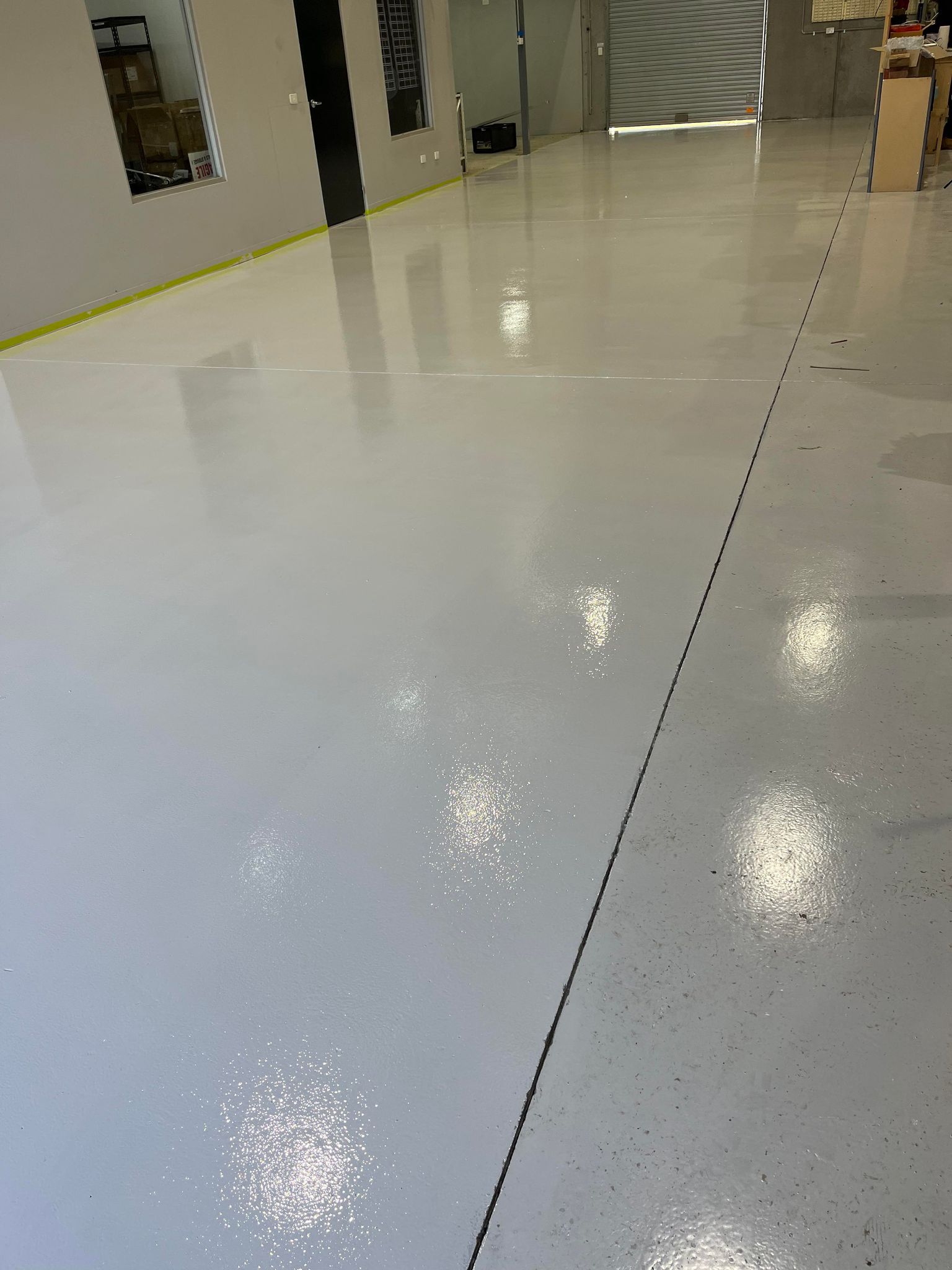 A large room with a white floor and a yellow tape on the floor