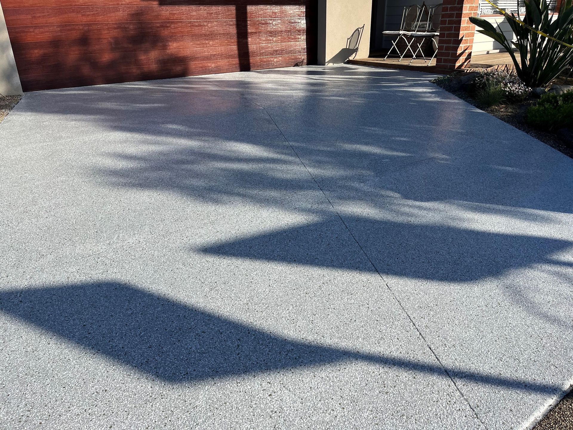 A driveway with a brick garage door and a shadow of a tree on it