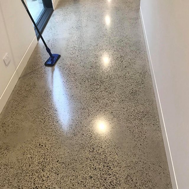A person is cleaning a concrete floor with a mop