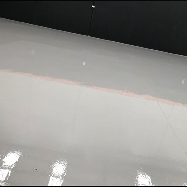 A close up of a white floor with a black wall in the background