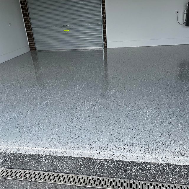 A garage with a gray floor and a drain