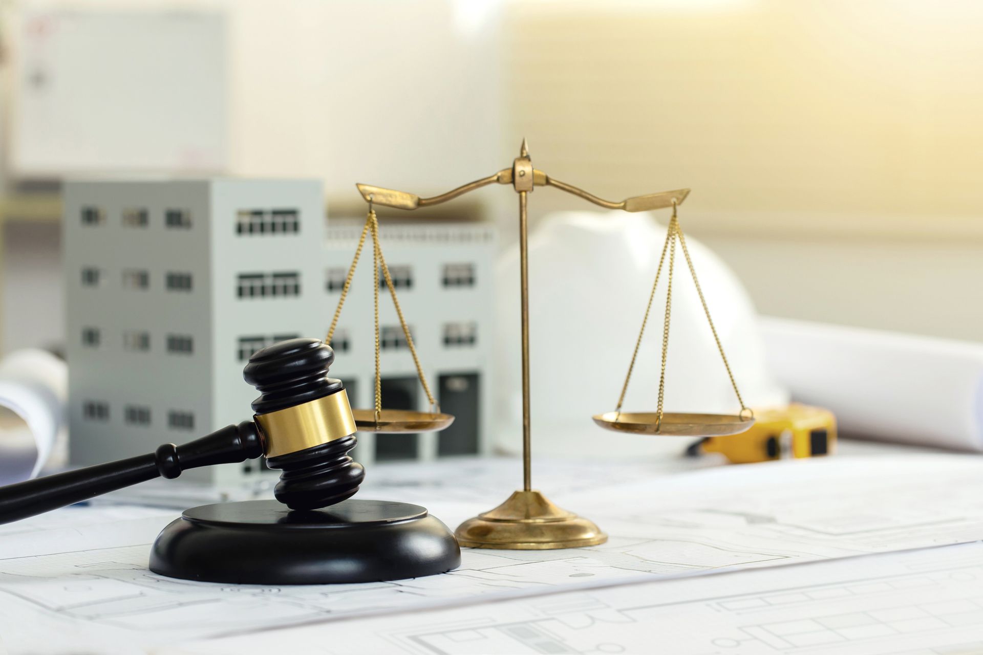 Gavel and scales of justice beside office buildings and blueprints on a desk