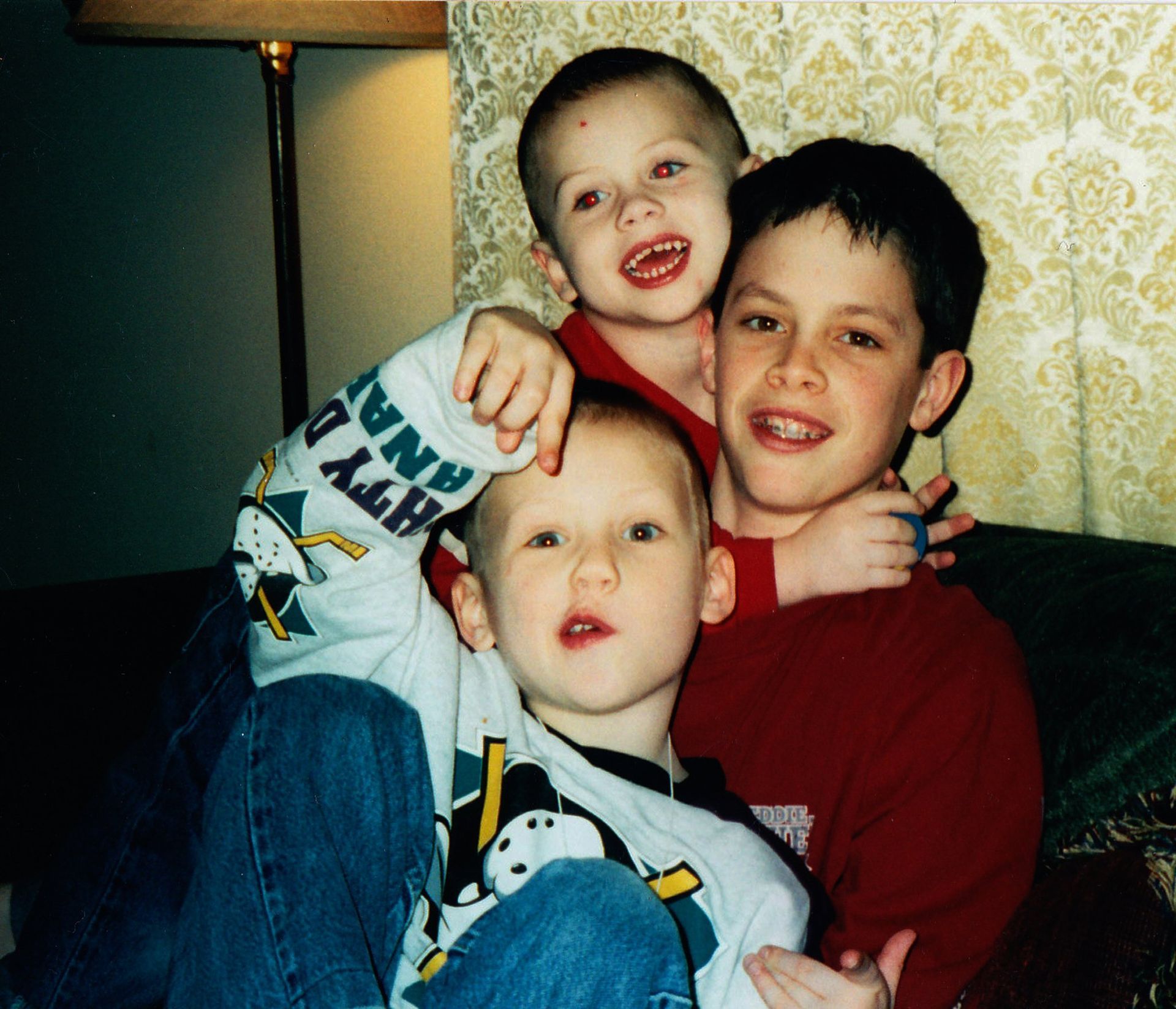 Three brothers posing for a goofy picture as children. 