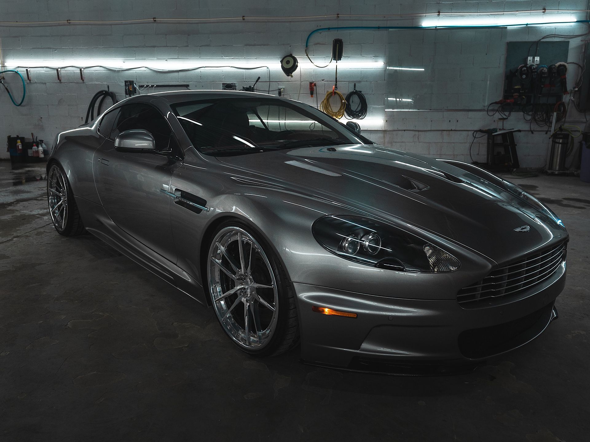 A gray sports car is parked in a garage.