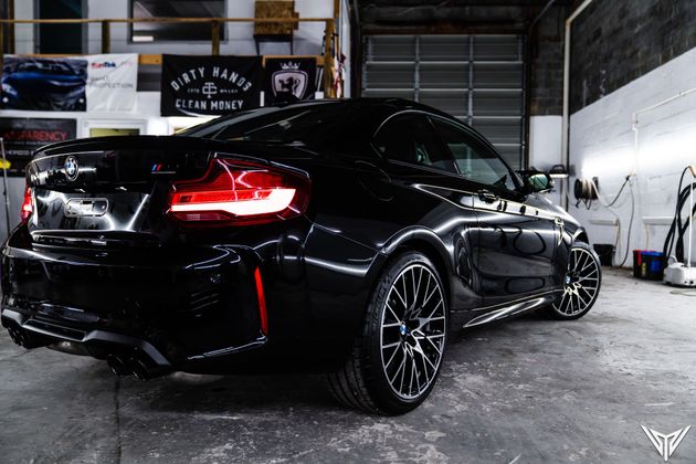 A black bmw m2 is parked in a garage.