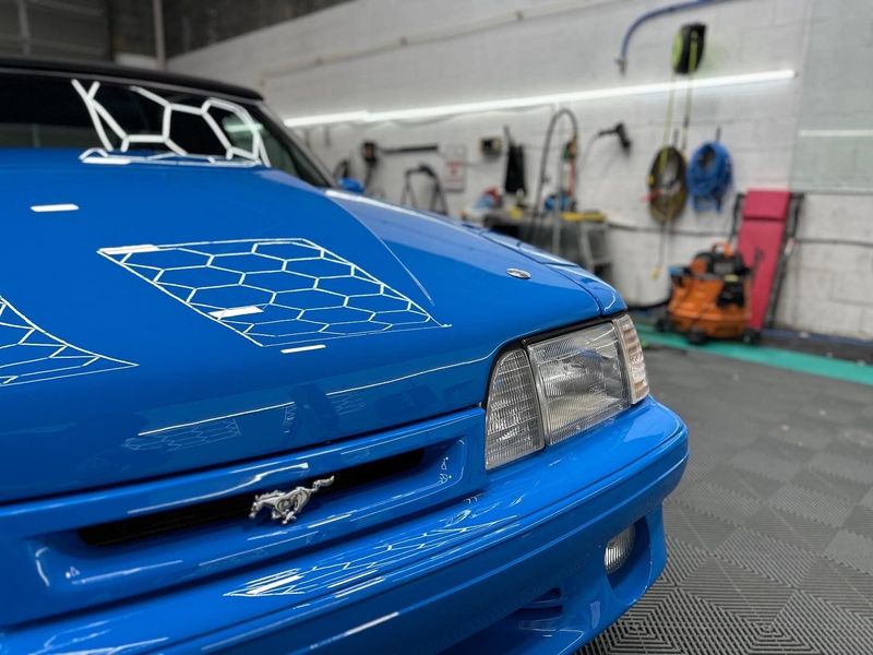 A blue mustang is parked in a garage.