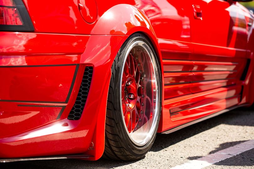 A red car is parked on the side of the road.