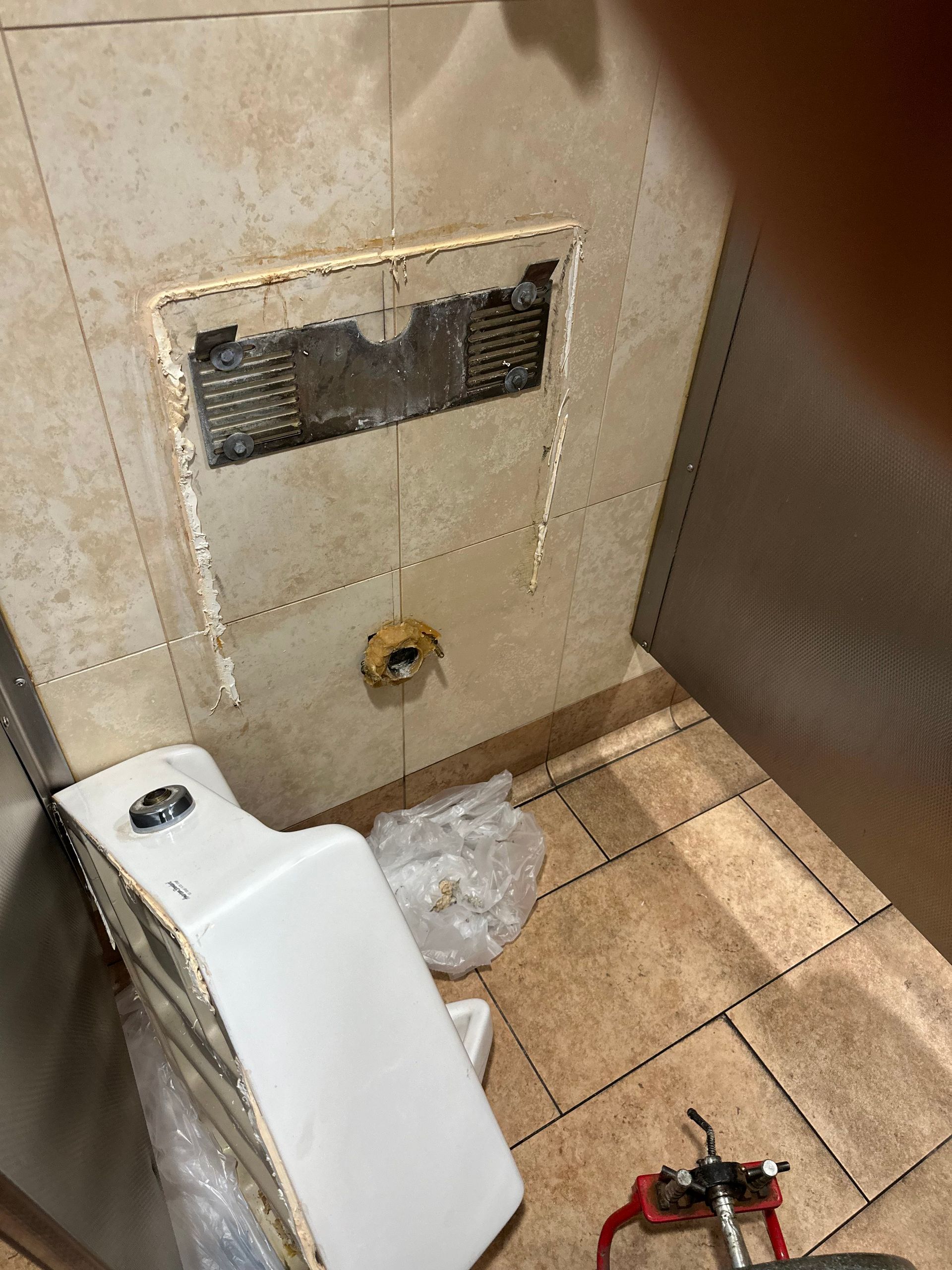 A toilet is sitting on the floor in a bathroom with a hole in the wall.