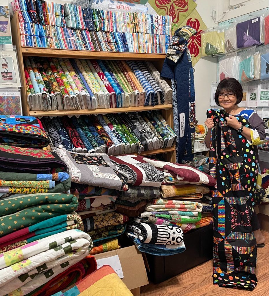 A woman is standing in a sewing shop holding a piece of fabric.