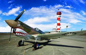 A fighter jet is parked on a runway with a lighthouse in the background.