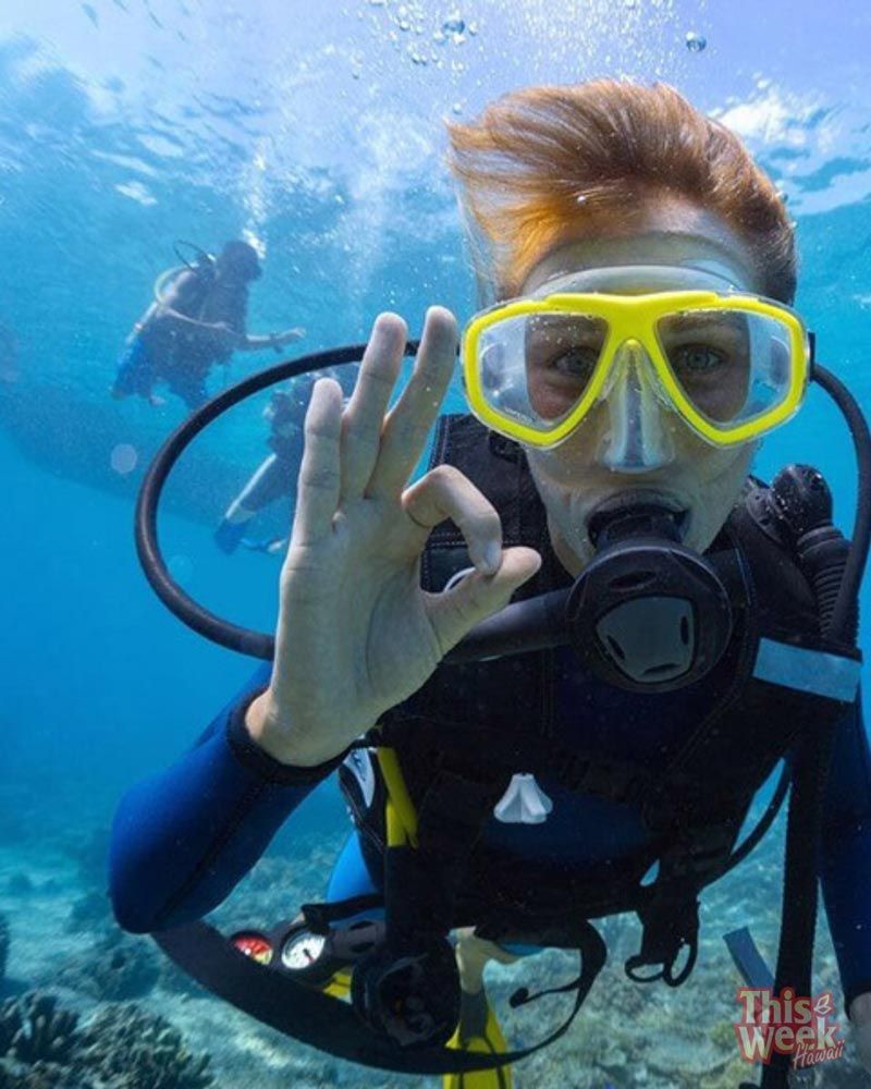 A scuba diver is giving the ok sign in the water