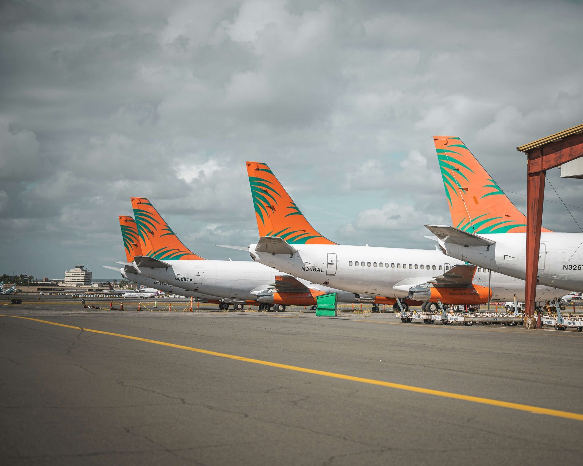 hawaiian airport runway with 3 planes and hawaiian designs on the tail