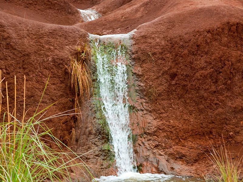 A small waterfall is coming down a rocky hillside.