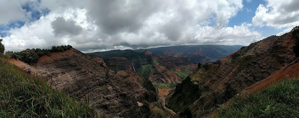 A panoramic view of a valley surrounded by mountains and trees on a cloudy day.