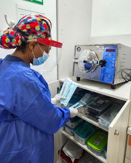 Dentista examinando los dientes de un paciente con un espejo dental y luz en una clínica.