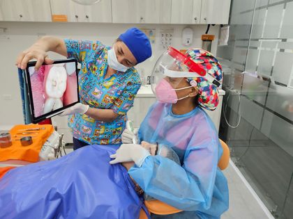 Dentista examinando los dientes de un paciente con un espejo dental y luz en una clínica.