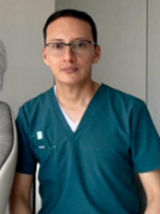 Manos enguantadas sosteniendo un cepillo de dientes con cerdas azules en un entorno de bata de laboratorio.