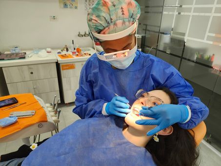 Dentista examinando los dientes de un paciente con un espejo dental y luz en una clínica.