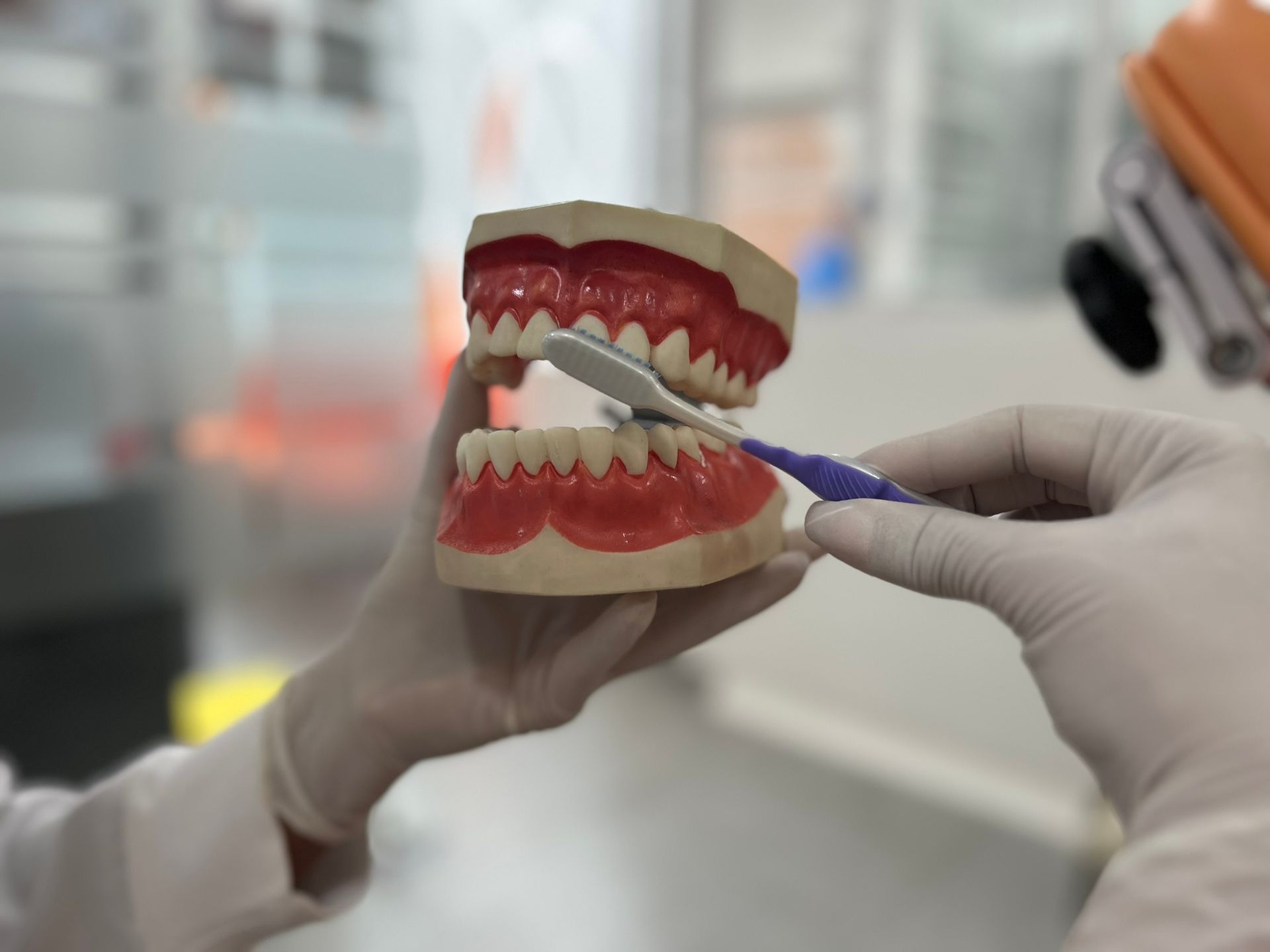 Un científico con bata blanca y gafas de seguridad toma notas mientras observa una muestra en un microscopio de laboratorio.